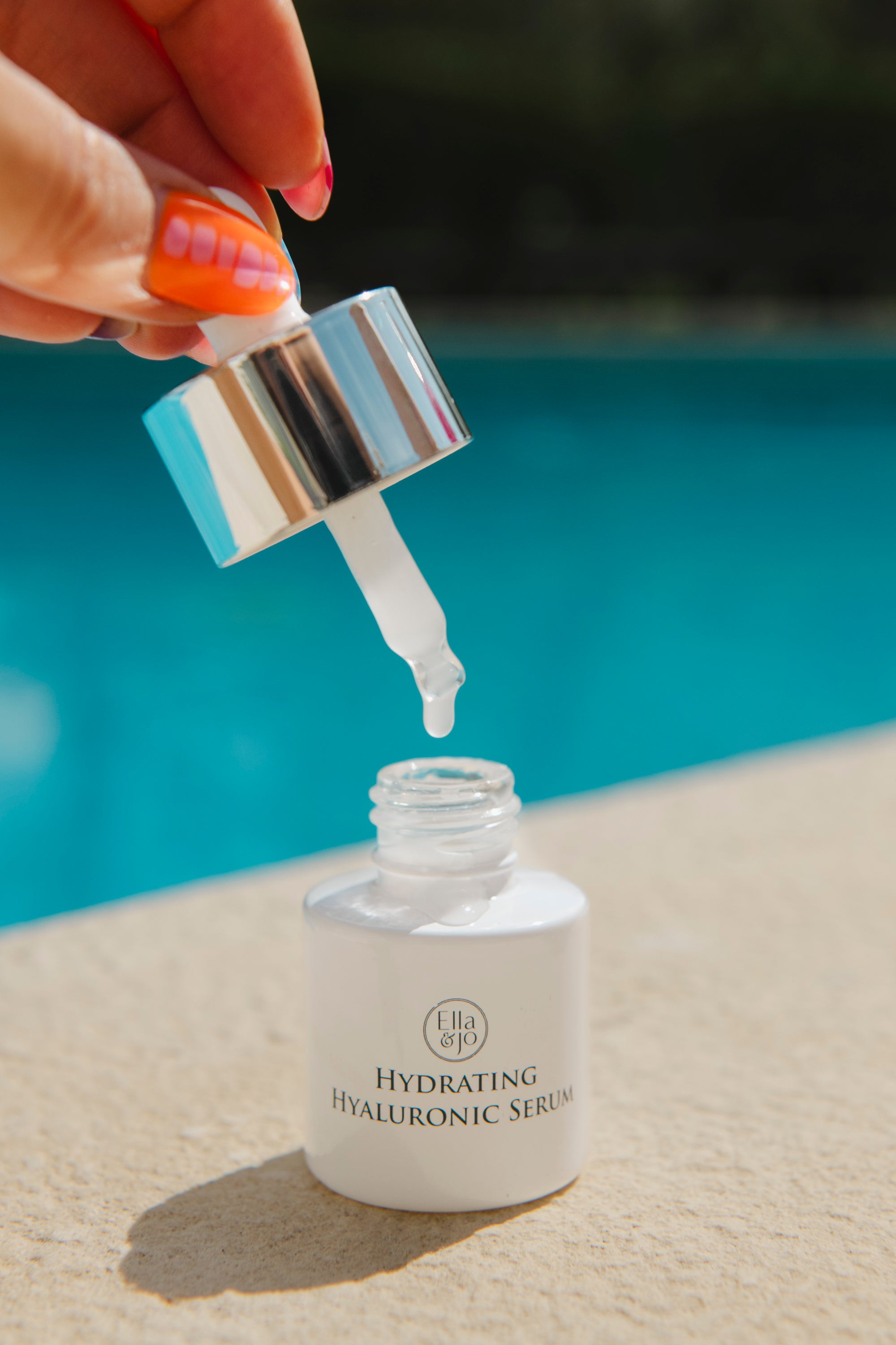 Hydrating Hyaluronic Serum being applied with a dropper against a blurred outdoor background.